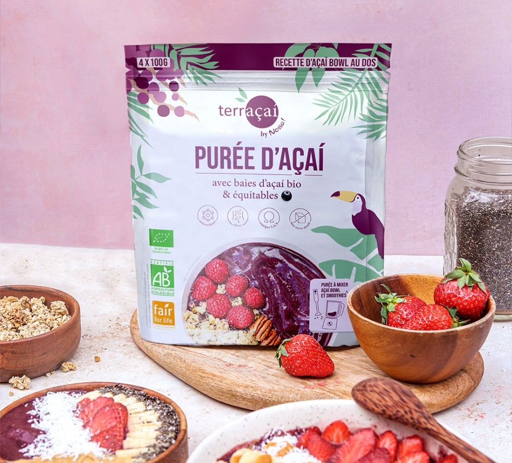 Tigela de açaí com bananas e morangos junto a um saco de puré de açaí congelado