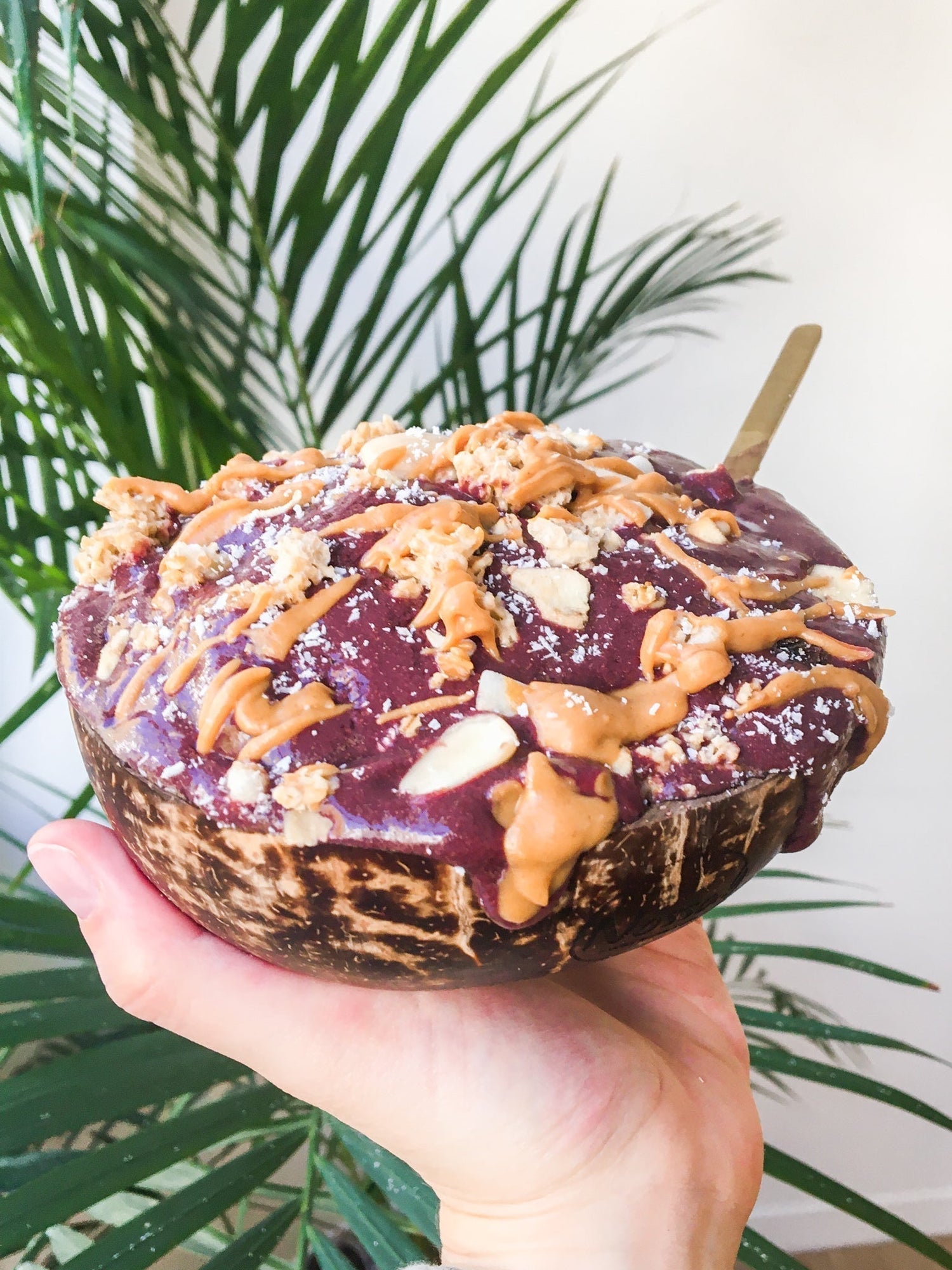 Una mano sosteniendo un bol proteico de acai